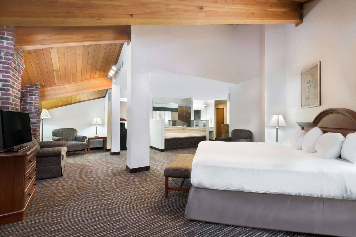A hotel room with a large bed, a TV, a fireplace, and a view of the city.