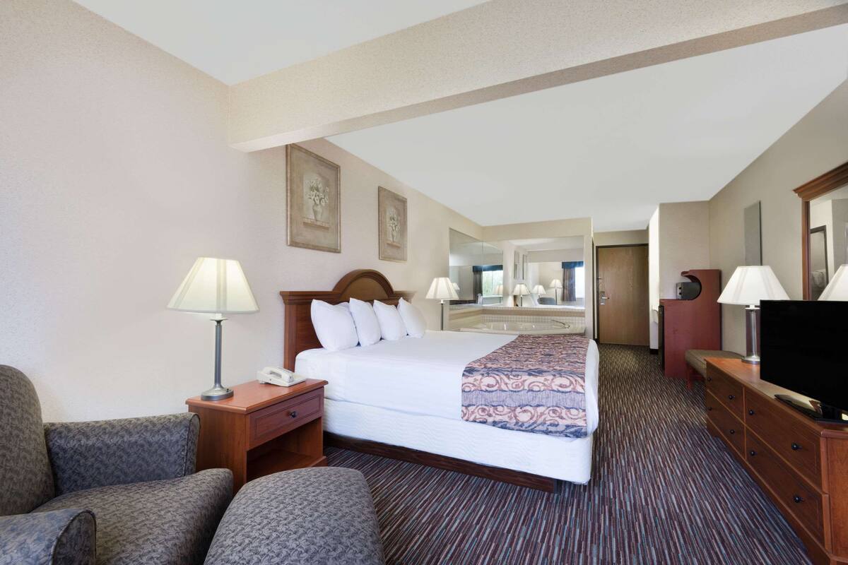A hotel room with a large bed, two bedside tables with lamps, a television, a desk, and a chair.