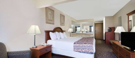 A hotel room with a large bed, two bedside tables with lamps, a television, a desk, and a chair.