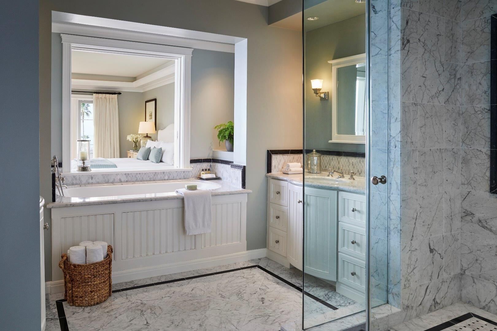 Une salle de bain dotée d’un grand miroir, d’une baignoire, d’une douche et d’un meuble-lavabo avec des placards.