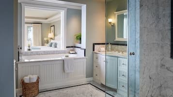 Une salle de bain dotée d’un grand miroir, d’une baignoire, d’une douche et d’un meuble-lavabo avec des placards.