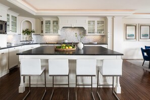 A kitchen with a large island, white cabinetry, and a backsplash.