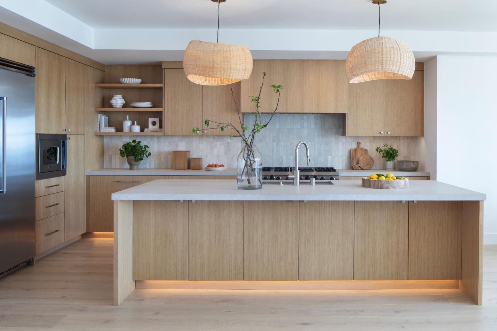 A modern kitchen with wooden cabinets, a central island, stainless steel appliances, and pendant lighting.