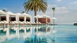 A poolside area with lounge chairs and umbrellas, a palm tree, and a clear sky. - Montage Laguna Beach (Laguna Beach)