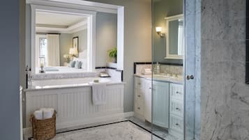 A modern bathroom with a large mirror, white vanity, marble flooring, and a glass shower enclosure.