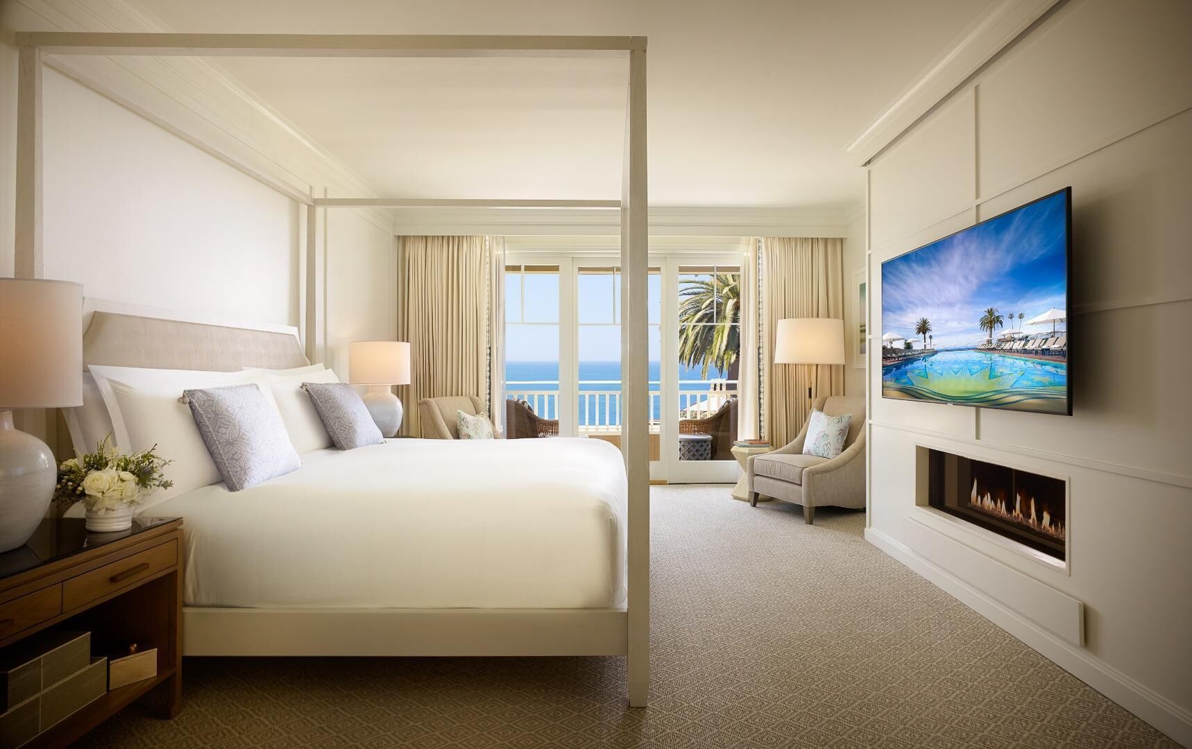 Ein Hotelzimmer mit Bett, Fernseher, Kamin und Meerblick.