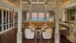 A spacious interior with a high ceiling, large windows offering a view of the sea, and a seating area with sofas and chairs. - Montage Laguna Beach (Laguna Beach)