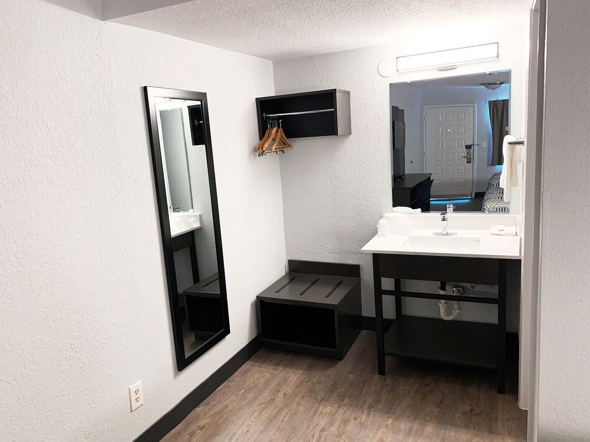 A compact bathroom with a white sink, a mirror, and a black cabinet.