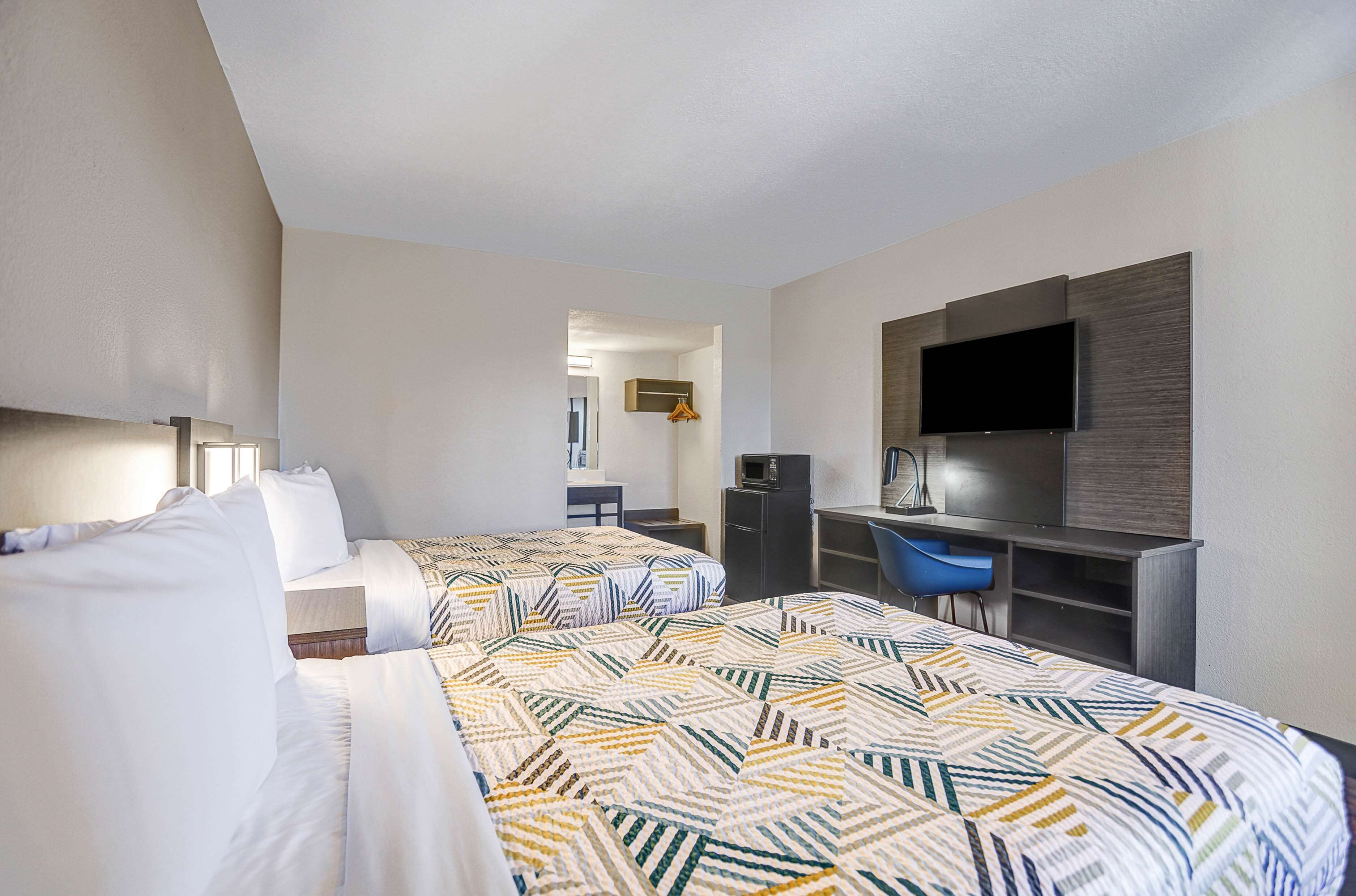 A hotel room with two beds, a desk, a chair, a TV, and a wardrobe.