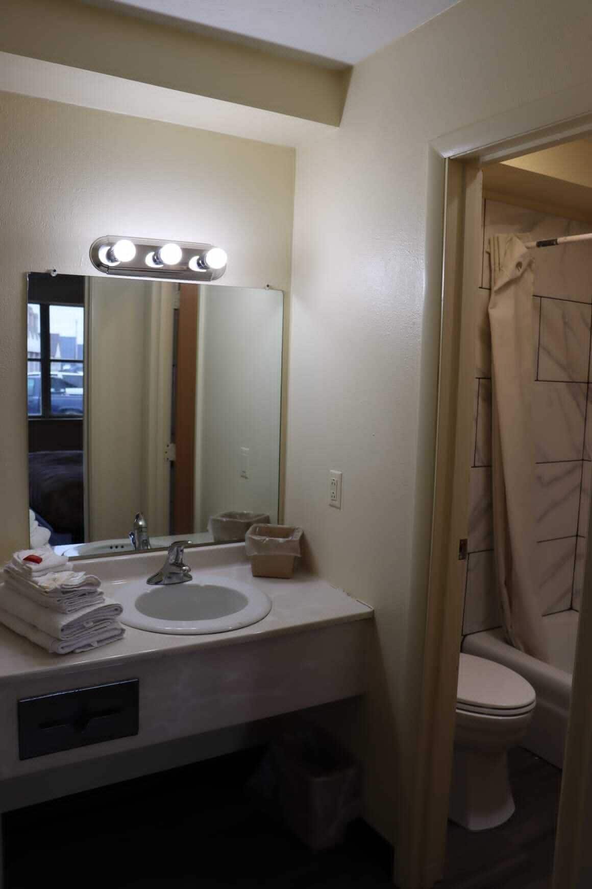 A bathroom with a sink, mirror, and a shower curtain.