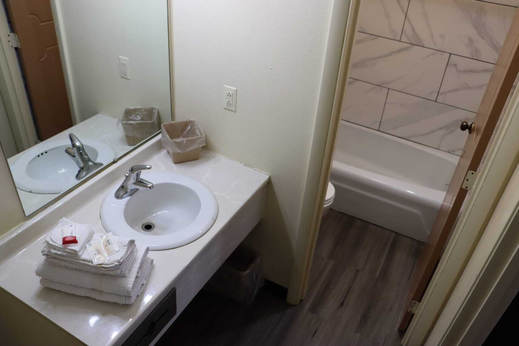 A bathroom with two sinks, a mirror, a toilet, and a bathtub.