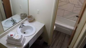 A bathroom with two sinks, a mirror, a toilet, and a bathtub.