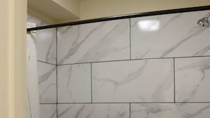 A bathroom with white marble tiles and a bathtub.