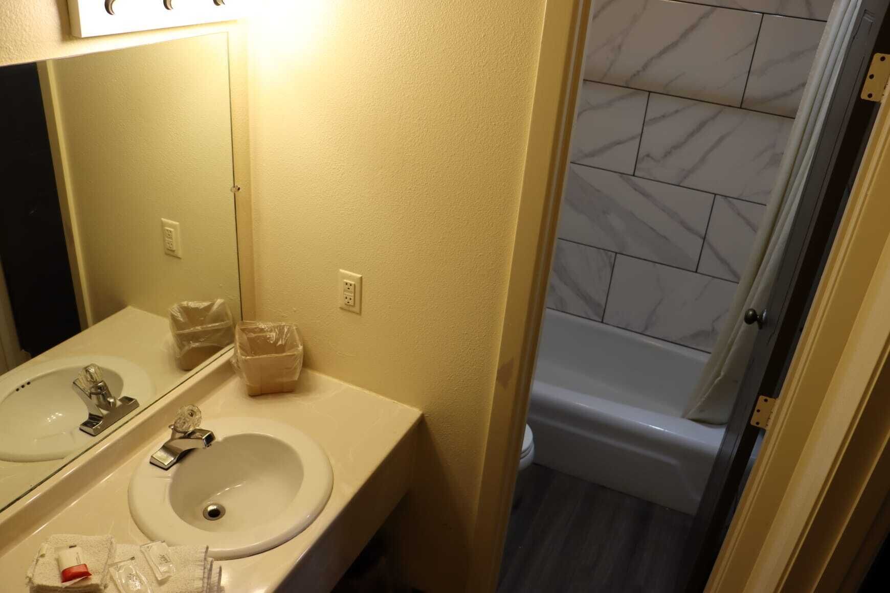 A bathroom with two sinks, a mirror, and a shower.