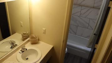 A bathroom with two sinks, a mirror, and a shower.