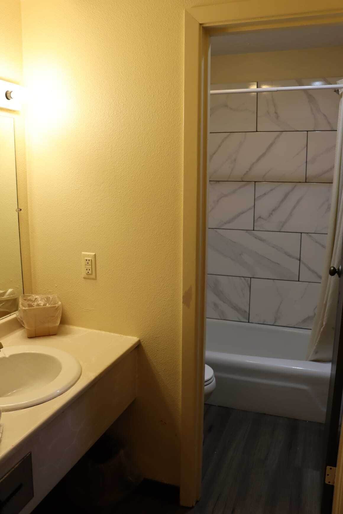 A bathroom with a white sink, mirror, and marble tiles.