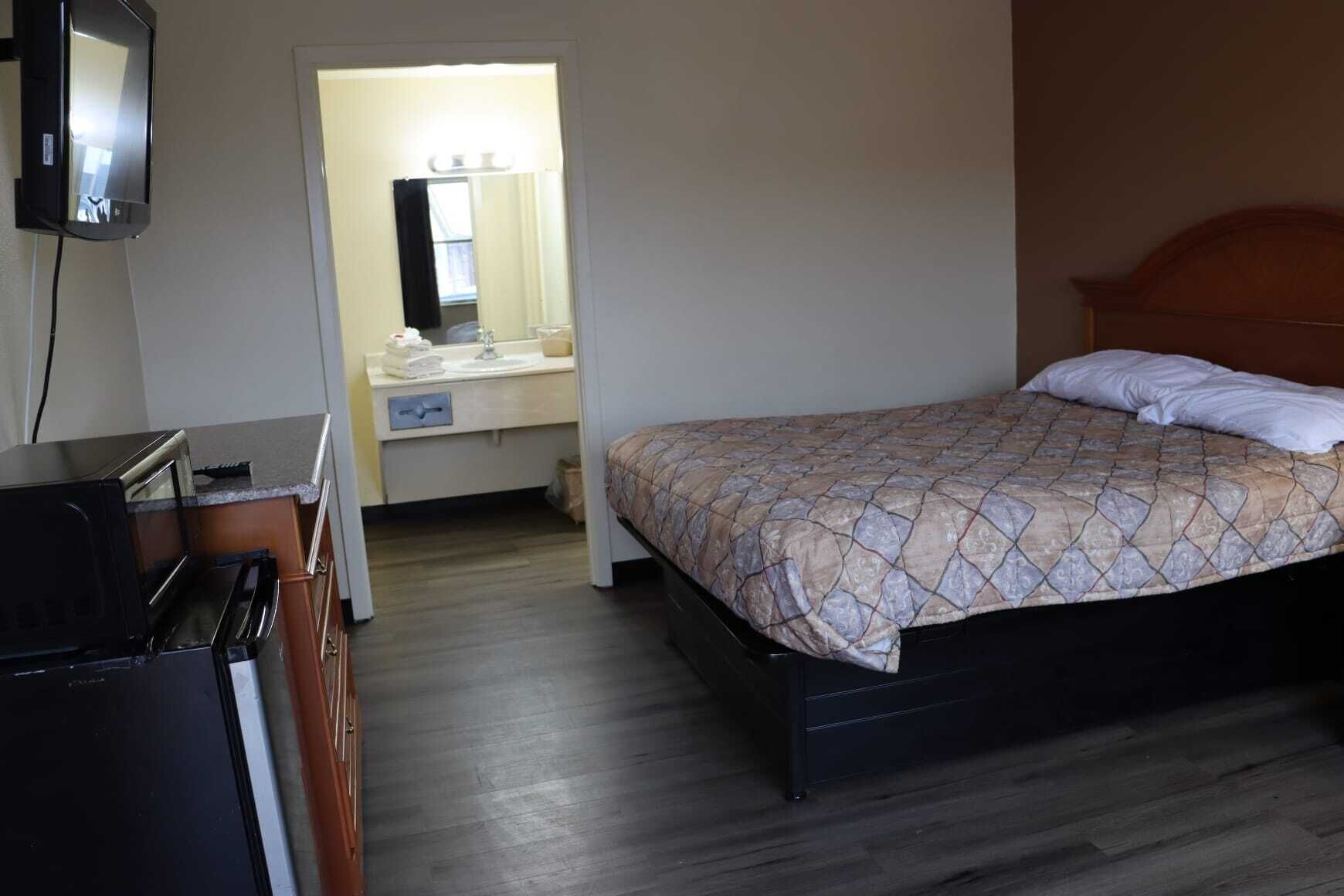 Une chambre d’hôtel avec un lit, un bureau, un miroir et une télévision.