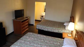 A hotel room with two beds, a TV, a dresser, and a lamp.