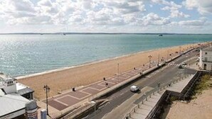 Une route côtière, avec une plage d’un côté et une autre route de l’autre.