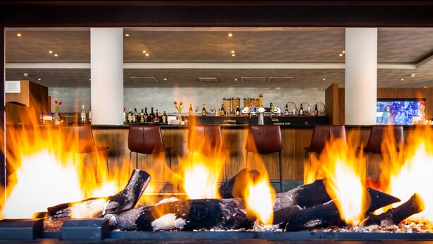 A bar area with a fireplace, bar counter, and seating. - Bastion Hotel Den Haag Rijswijk (Rijswijk)