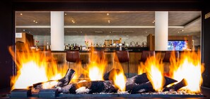 A bar area with a fireplace, bar counter, and seating. - Bastion Hotel Den Haag Rijswijk (Rijswijk)