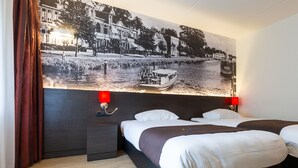 A hotel room with a large bed, two bedside tables, a nightstand, and a wall-mounted lamp. - Bastion Hotel Den Haag Rijswijk (Rijswijk)