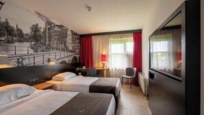 A hotel room with two beds, a desk, a chair, a TV, and a large window with red curtains. - Bastion Hotel Schiphol Hoofddorp (Hoofddorp)