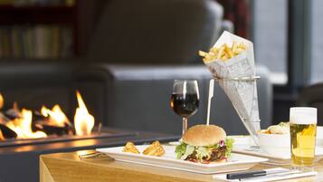 Una mesa de comedor con una hamburguesa, papas fritas, una copa de vino y una cerveza.