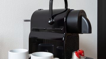 Una máquina de café espresso negra con dos tazas blancas que dicen 'Bastion Hotels.NL' sobre una superficie de madera.