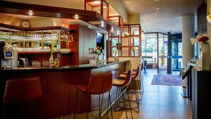 A bar area with stools, a counter, and a television screen. - Bastion Hotel Utrecht (Utrecht)