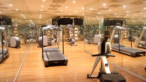 A gym with exercise equipment, mirrors, and a wooden floor. - Bastion Hotel Amsterdam Amstel (Amsterdam-Duivendrecht)