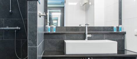 A modern bathroom with a large mirror, a white sink, and a shower area.