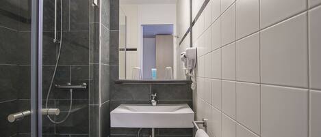 A modern bathroom with a glass-enclosed shower, a white sink, and a towel rack.