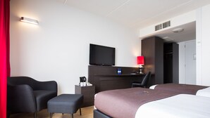 Une chambre d’hôtel moderne équipée d’un lit, d’un bureau, d’une chaise et d’un téléviseur.