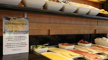 A breakfast buffet with various food options and a sign offering choices like boiled eggs and omelets.