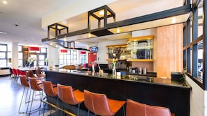 Una zona de bar moderna con una barra larga, varios taburetes y una variedad de utensilios y botellas.