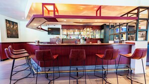 A bar area with a high counter, multiple stools, and a television screen. - Bastion Hotel Rotterdam Zuid (Rotterdam)