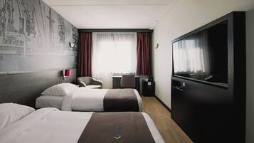 Een hotelkamer met twee bedden, een bureau, een stoel, een televisie en een muurschildering.