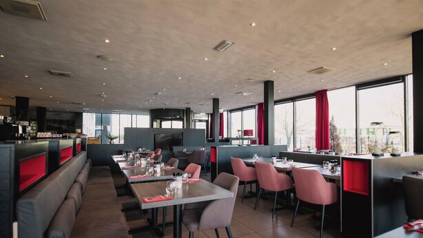 A modern restaurant with booths and tables, large windows, and a high ceiling. - Bastion Hotel Rotterdam Zuid (Rotterdam)