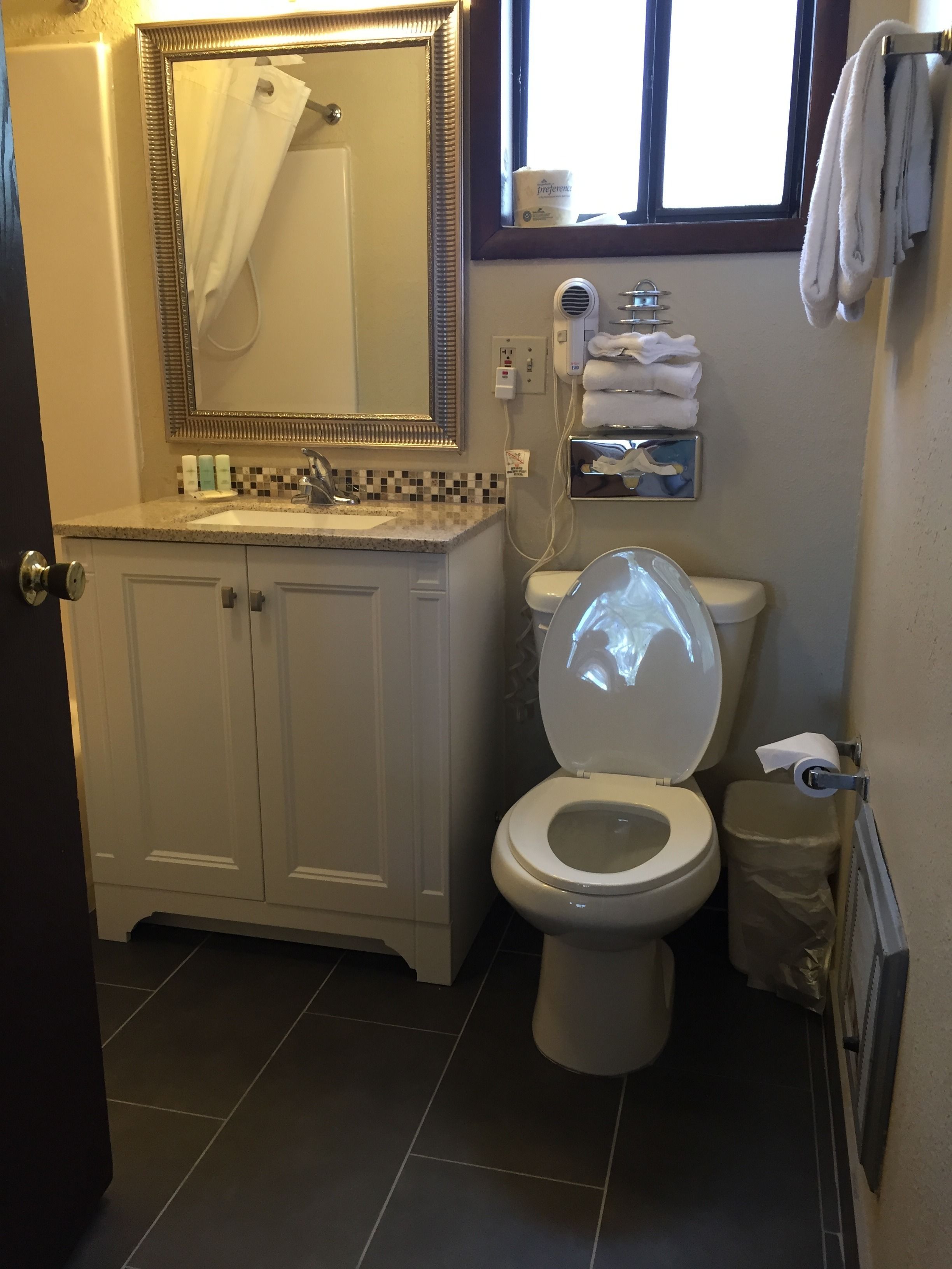 A bathroom with a toilet, sink, and mirror.