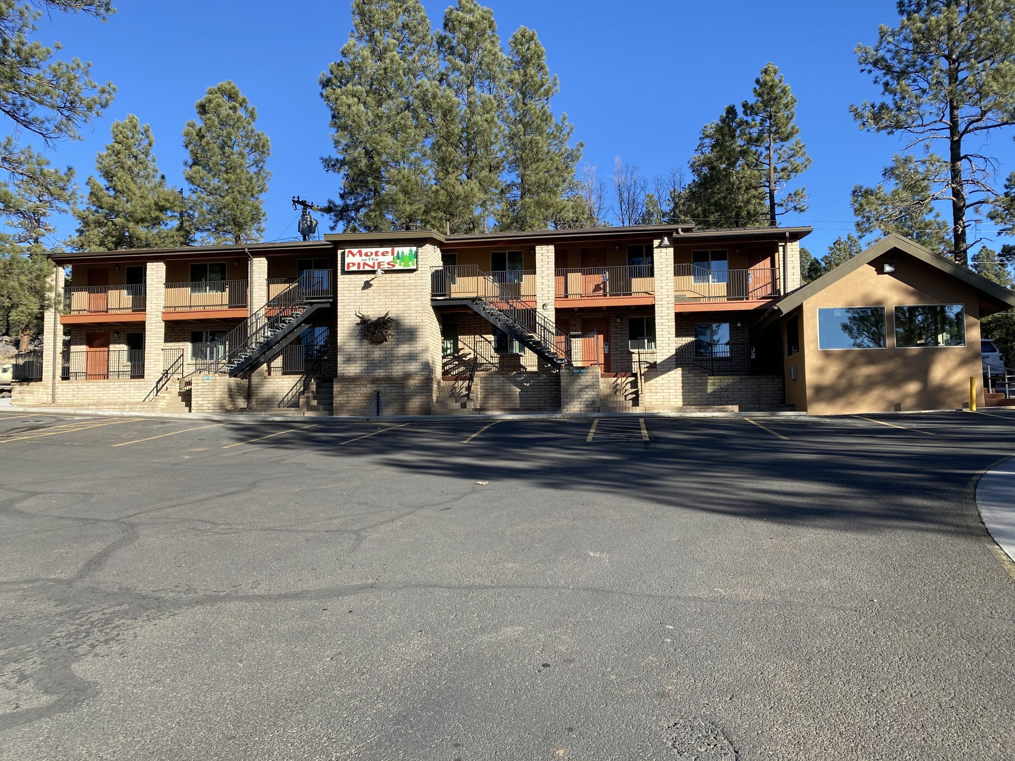 A motel with a sign reading "Motel Pines" and a parking lot in front.