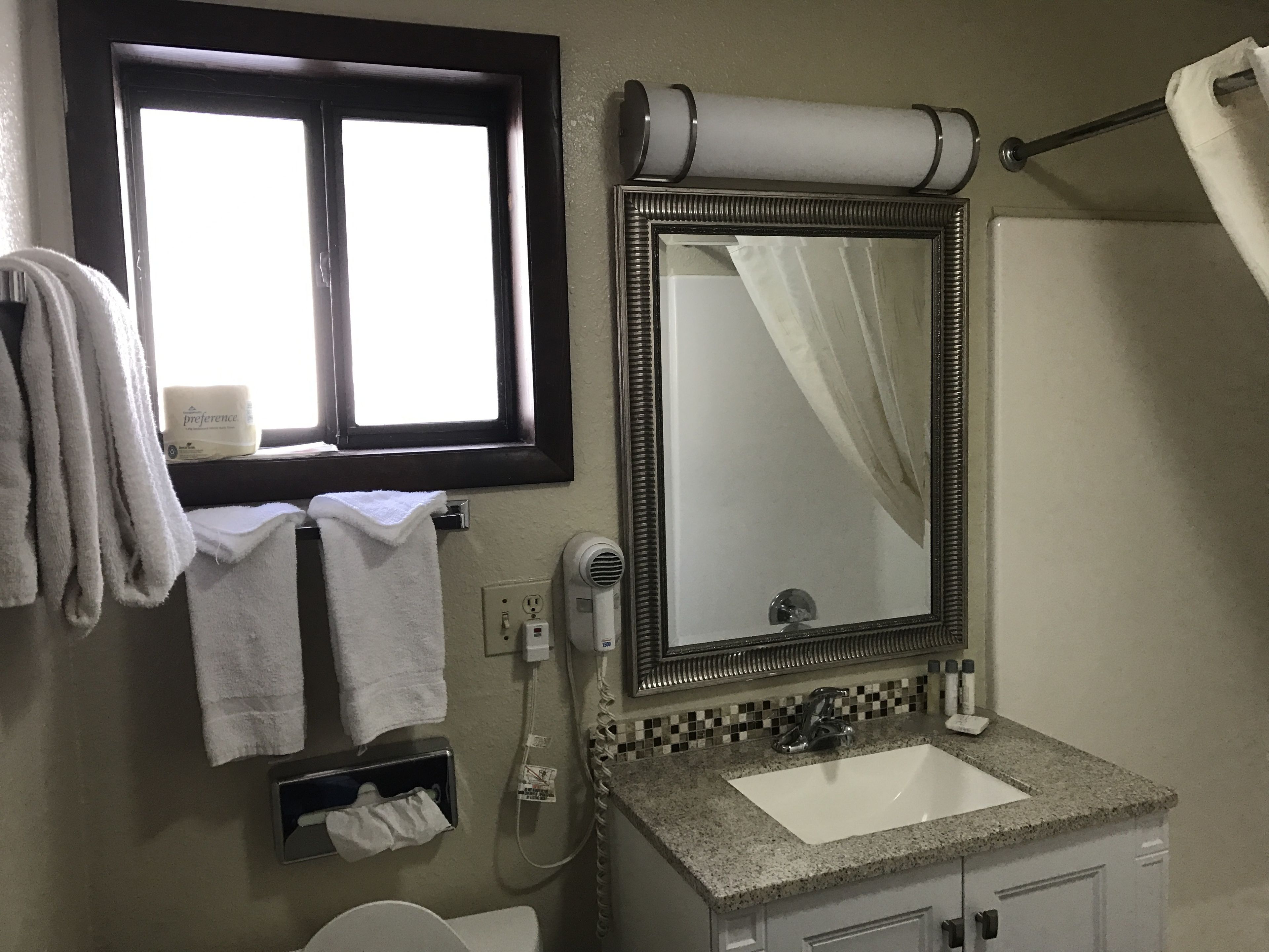 Un baño con lavabo, espejo, toallero y ventana.