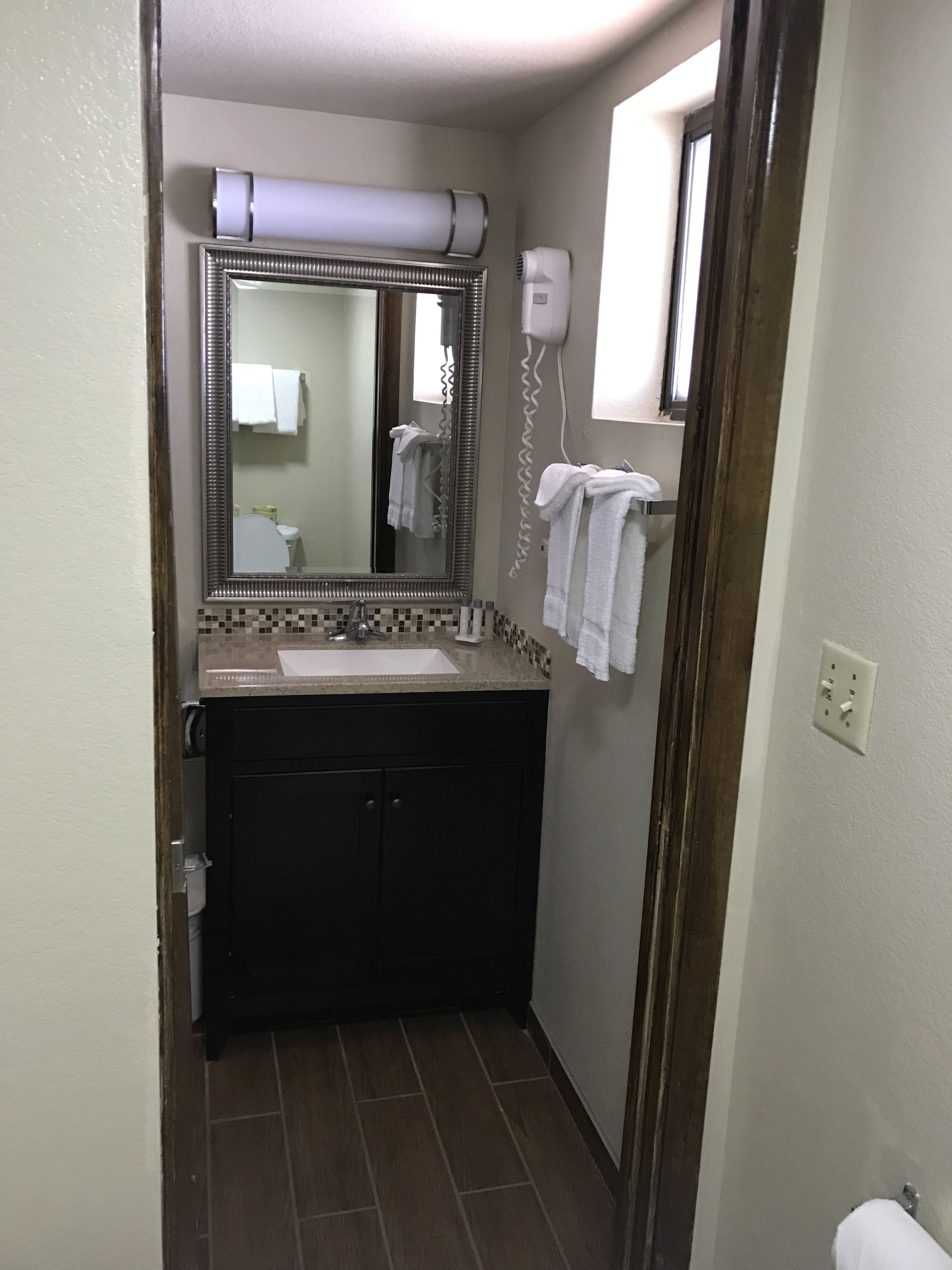 A bathroom with a sink, mirror, towel rack, and a hairdryer.