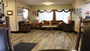 A living room with a brown sofa, two armchairs, a coffee table, and a fireplace. - Aero Inn (Kalispell)