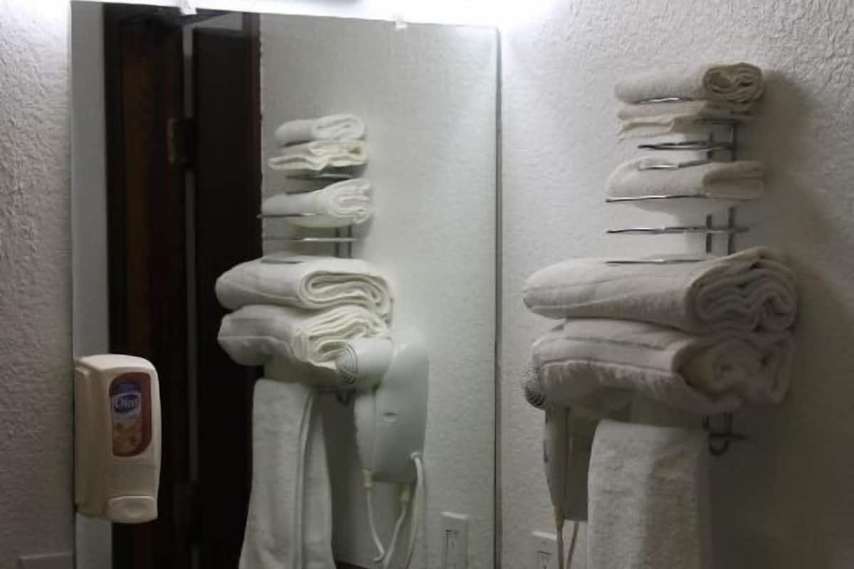 Ein Badezimmer mit Waschbecken, Spiegel und Handtüchern auf einem Ablagegestell.