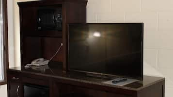 A dark wooden entertainment center with a flat-screen TV and a microwave.