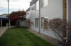 A modern two-story building with a well-maintained lawn and a tree with red leaves.
