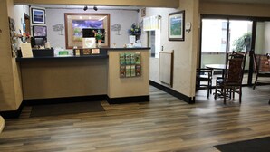 A reception area with a wooden floor, a reception desk, framed artwork, and a dining area with chairs and a table. - Aero Inn (Kalispell)