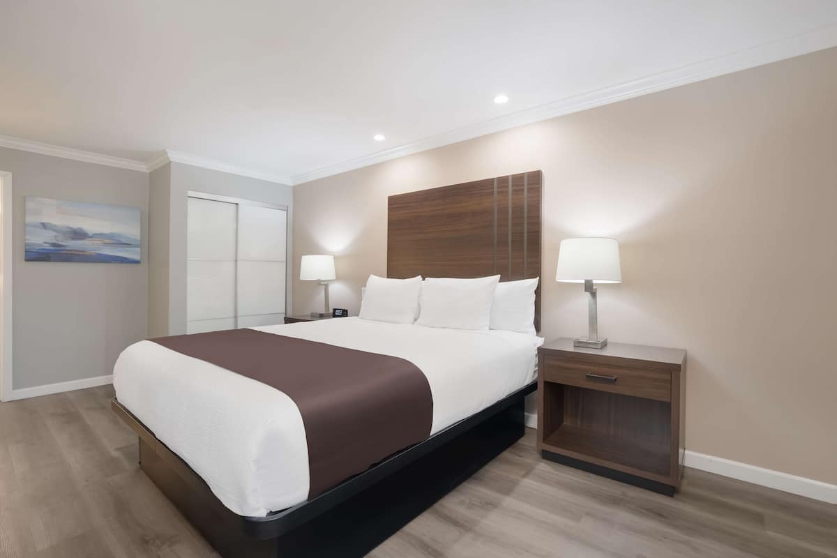Una habitación de hotel moderna con una cama grande, mesitas de noche y una mesita auxiliar.