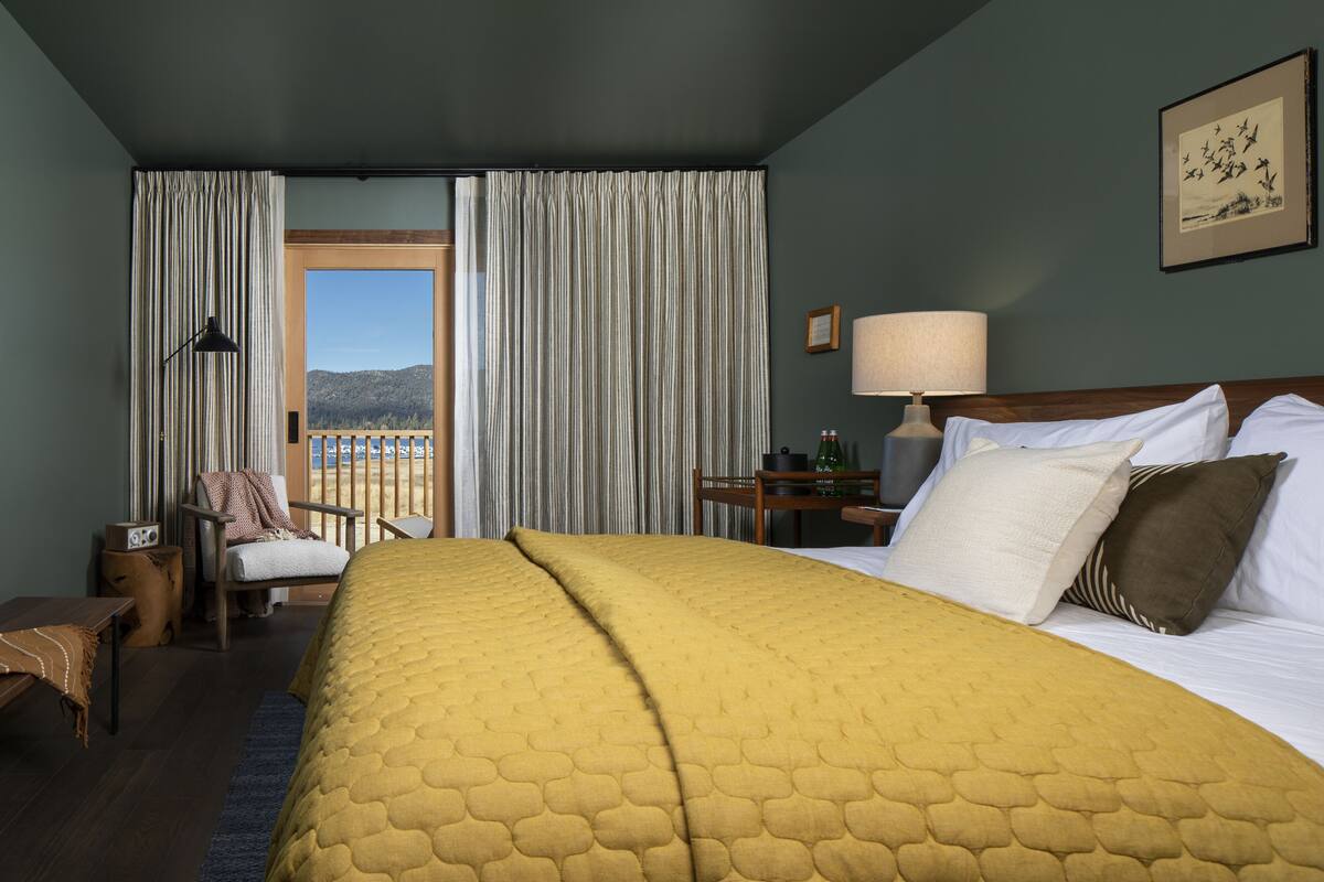 A hotel room with a large bed, a chair, a desk, and a view of the outdoors.